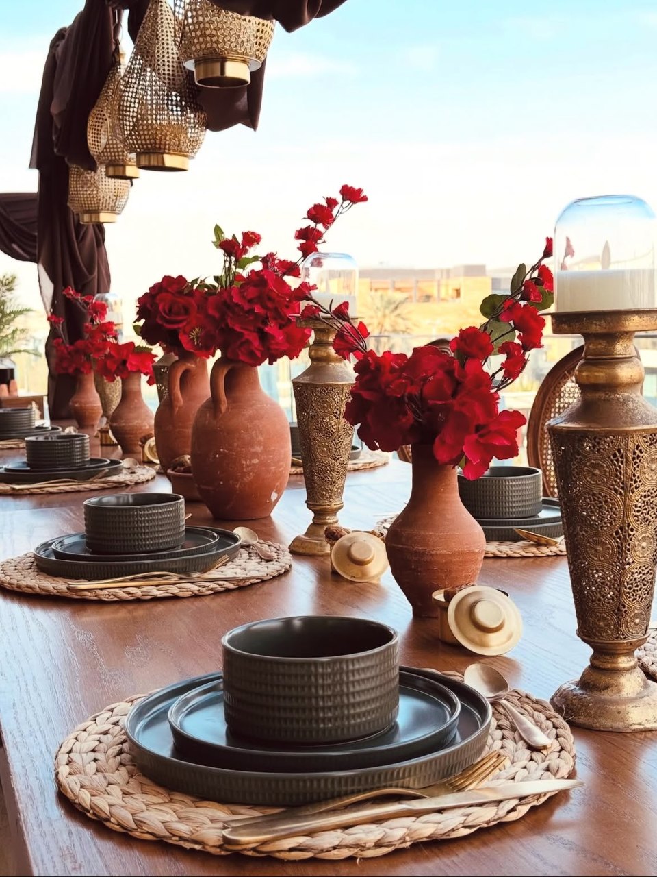 Styled banquet table with terracotta vases, red florals and brass lanterns by DT Events